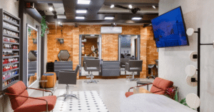 Interior do Beauty.Co.Lab na Vila Nova Conceição, com estações de atendimento, espelhos, poltronas em tons terrosos, parede de tijolos e elementos naturais.
